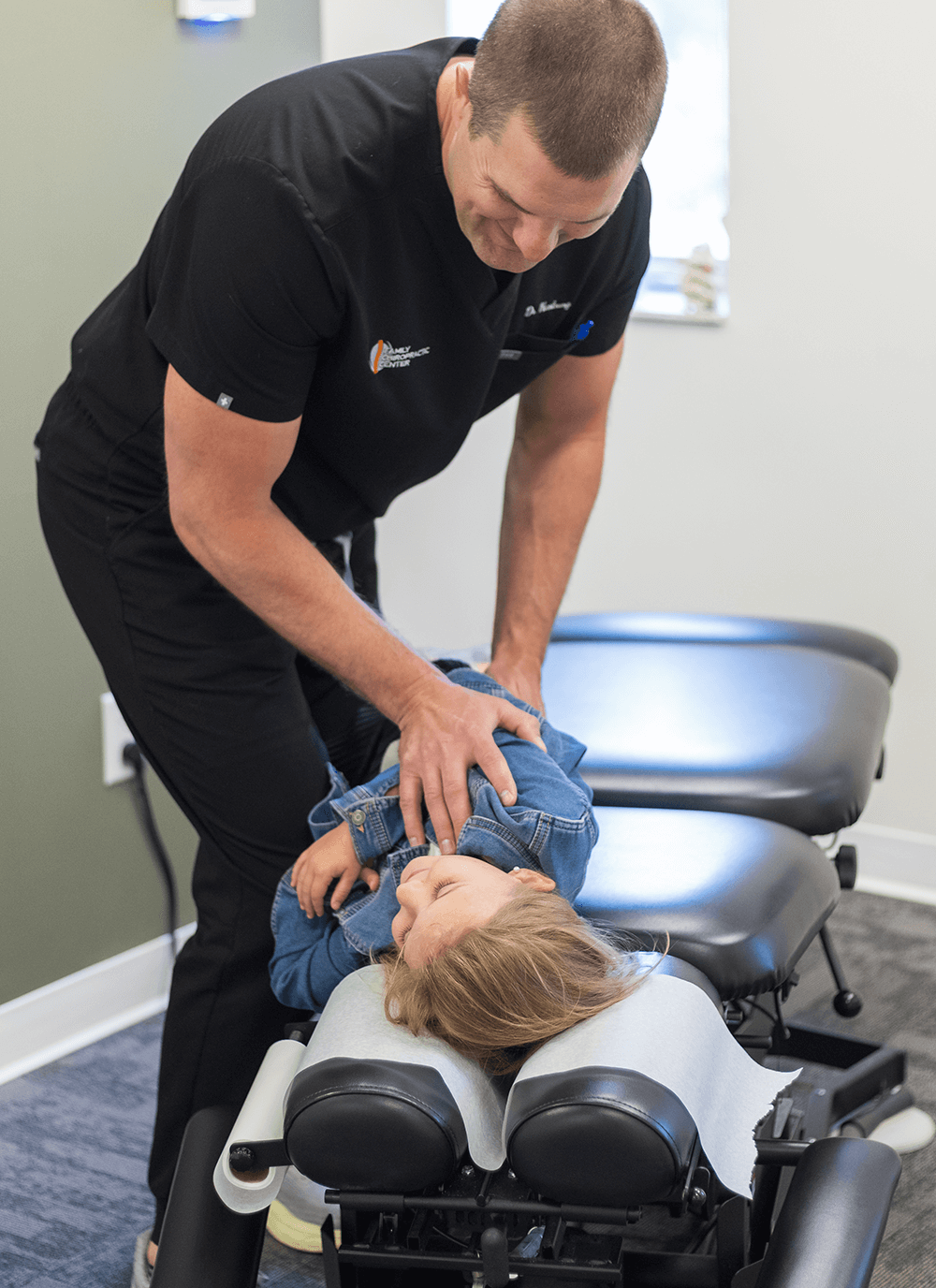 Dr. Kevin Hartung performing a gentle adjustment on a child lying on a chiropractic table.
