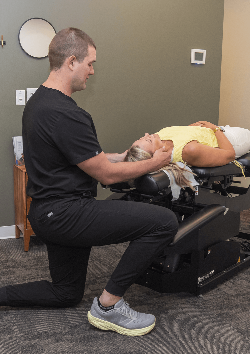 Dr. Kevin Hartung performing a gentle neck adjustment on a patient lying on a treatment table.